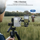 A content creator operates a camera and smartphone on a tripod, capturing footage of a man standing in a grassy field 100 meters away.